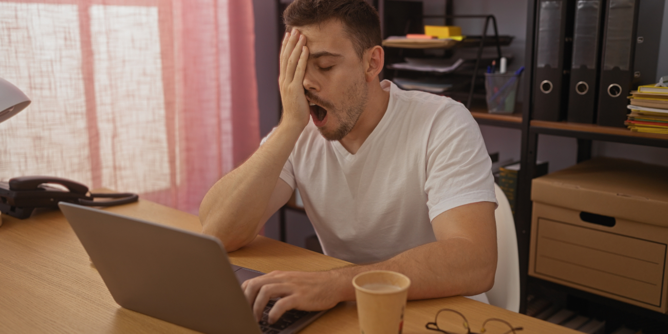 Uomo che sbadiglia davanti allo schermo del computer a causa della sonnolenza