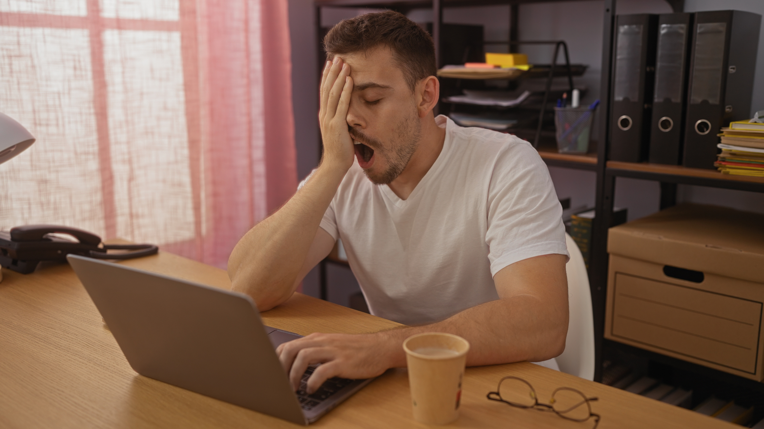 Uomo che sbadiglia davanti allo schermo del computer a causa della sonnolenza
